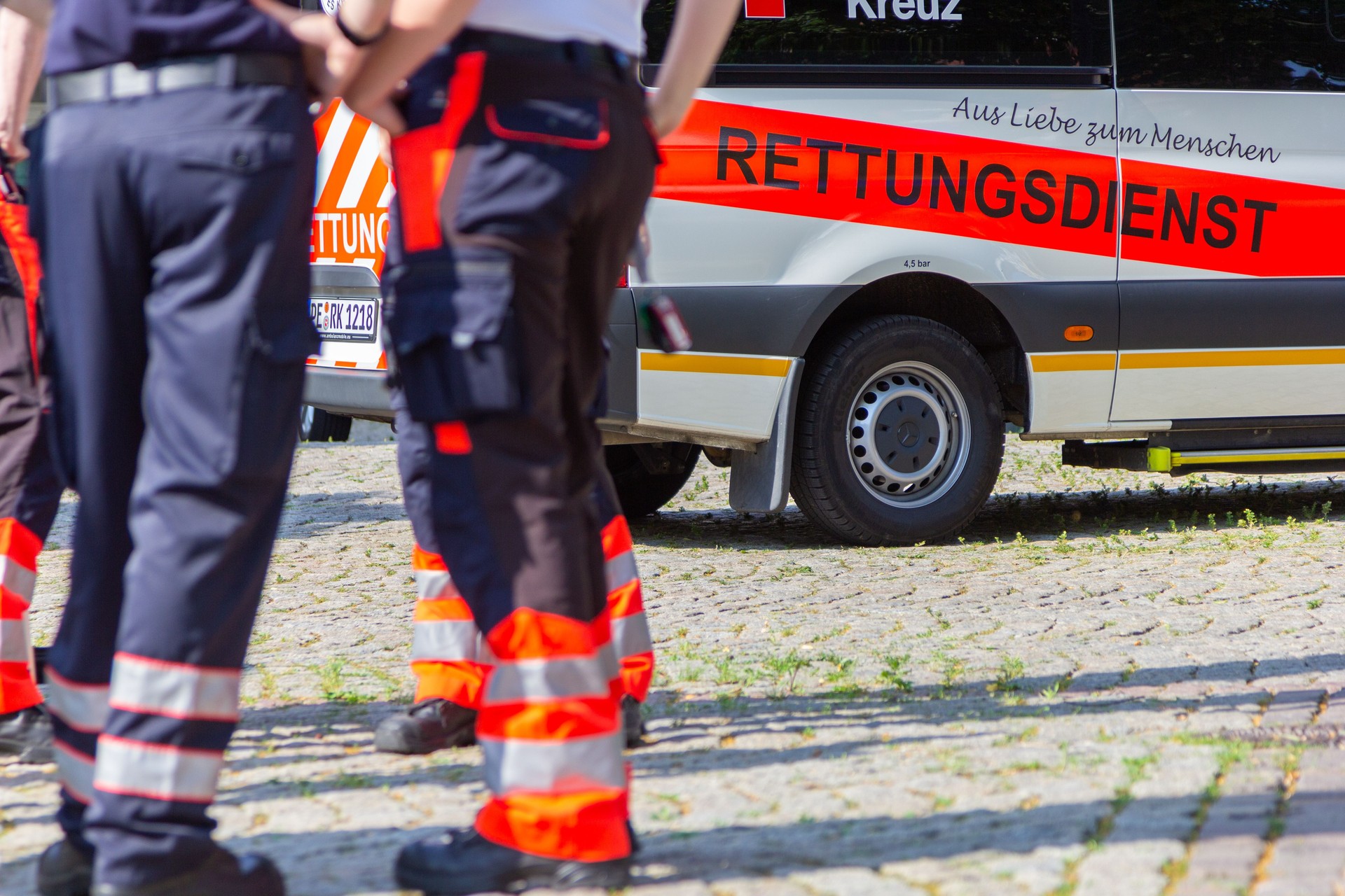 German female paramedic stands in front of an ambulance car.